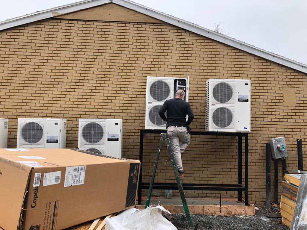 Technician commissioning multi-zone condensers on a wall-mounted rack
