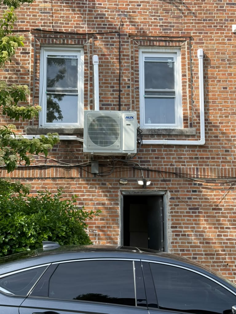 Ductless mini split condenser installed on a brick home